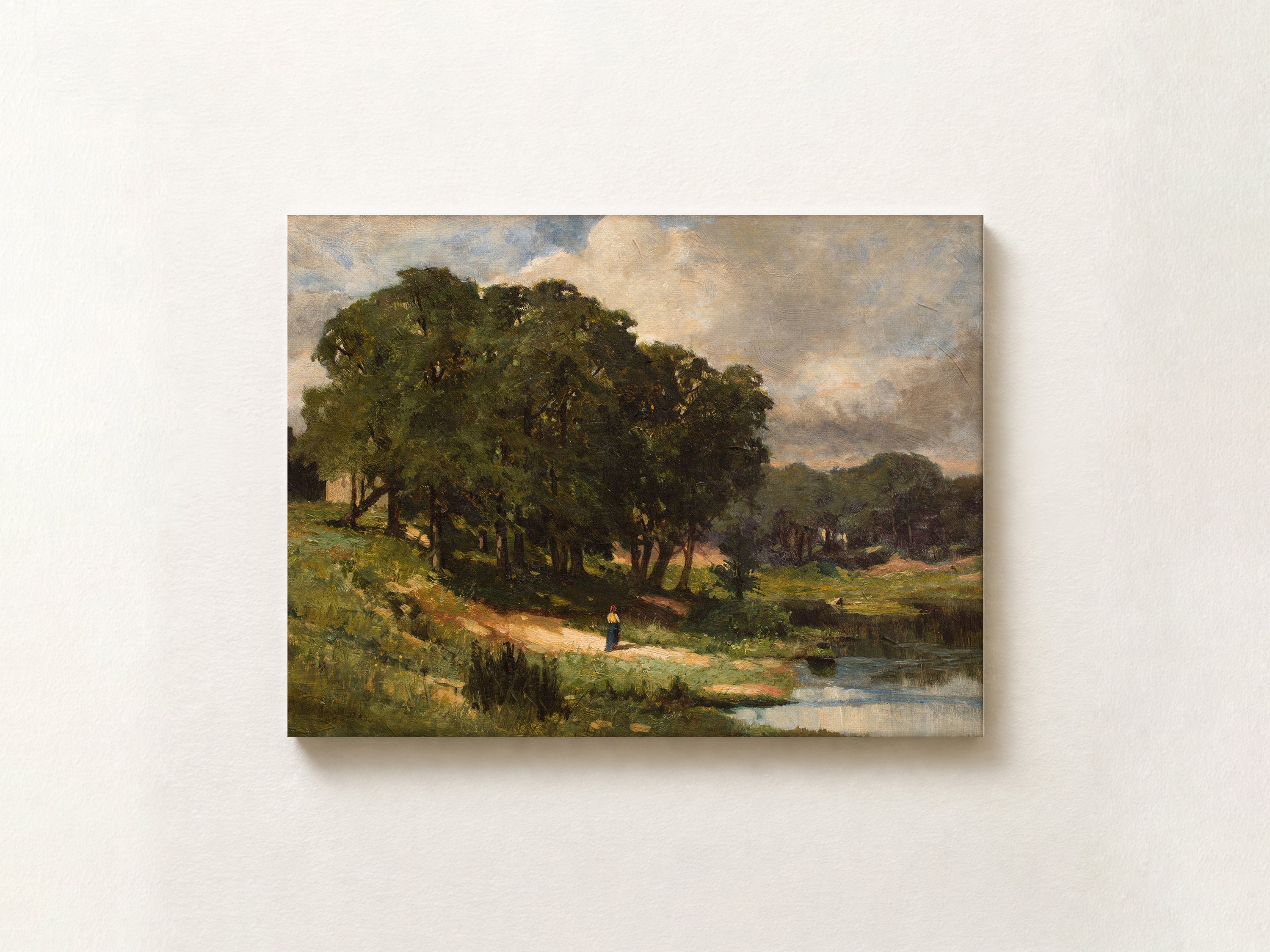 A framed landscape art print depicting a serene park scene with a large tree, grassy field, and a small figure near a river, displayed on a light beige wall.