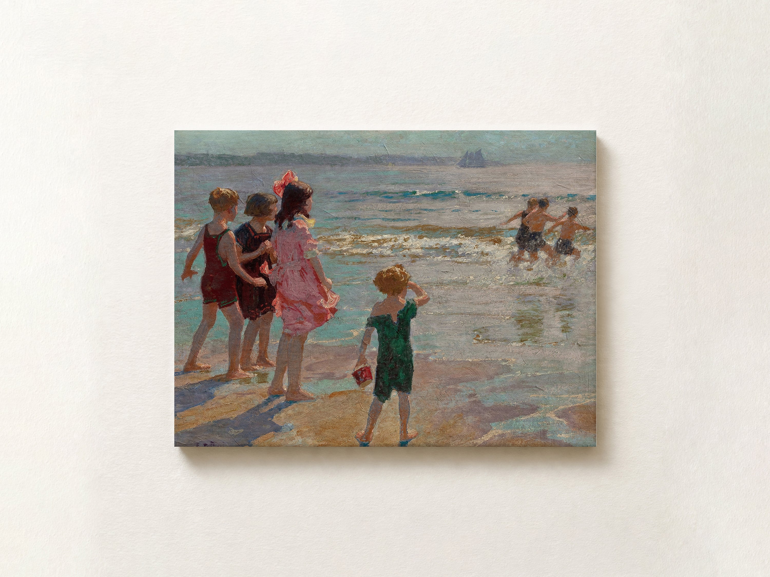 An impressionist oil painting print depicting children playing on a beach, shown hanging on a textured off-white wall.