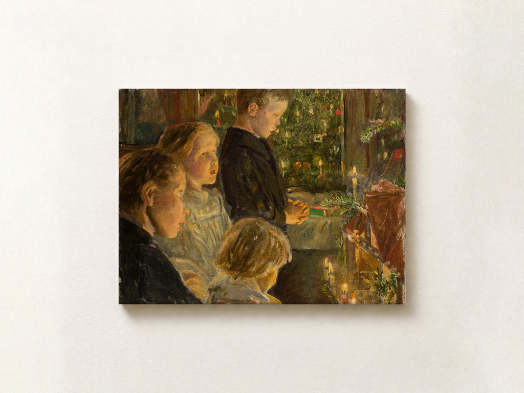 A horizontal canvas print of a classic oil painting depicting children gathered around a table with candles and a decorated Christmas tree, mounted on a textured off-white wall.