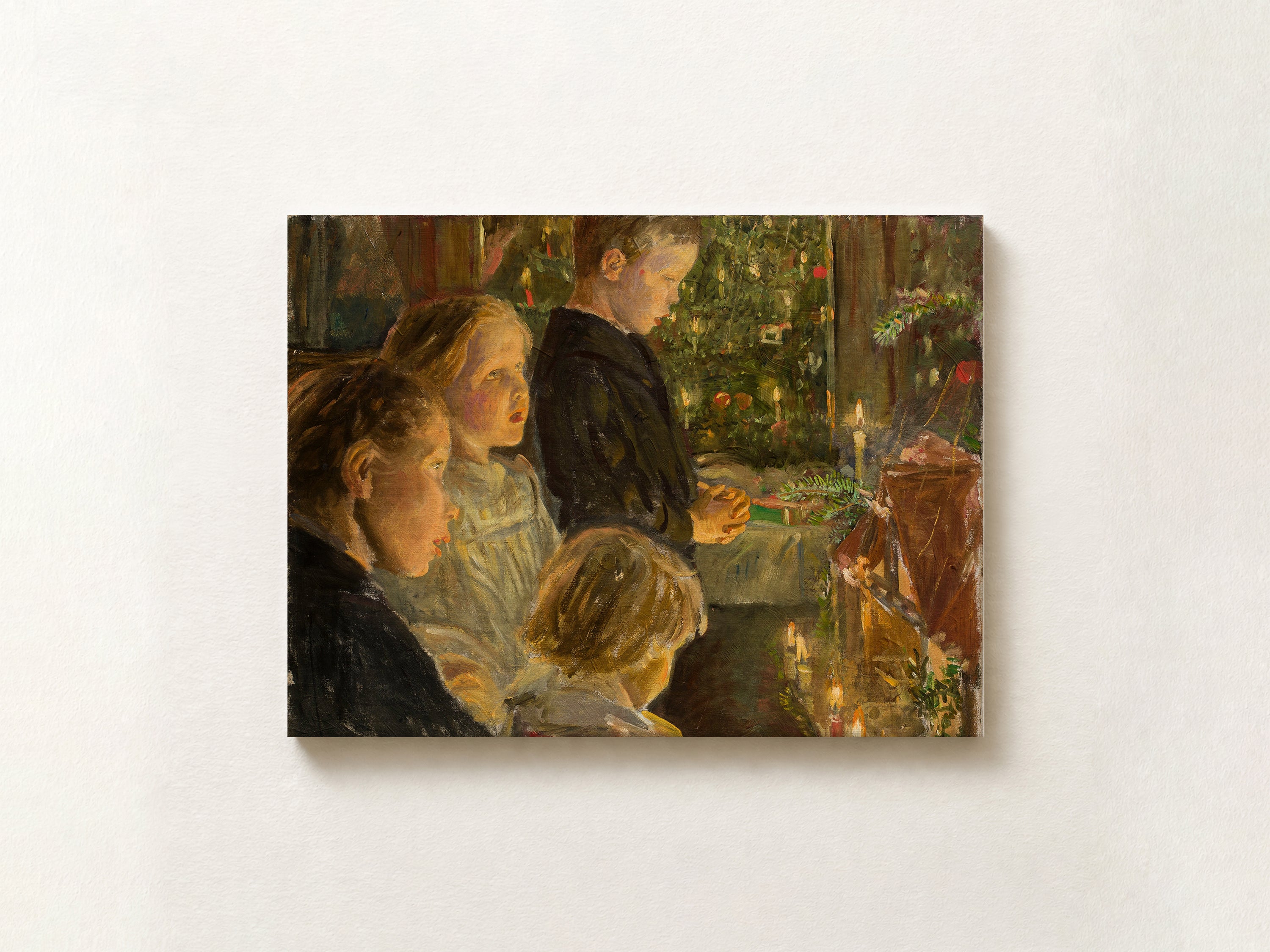 A horizontal canvas print of a classic oil painting depicting children gathered around a table with candles and a decorated Christmas tree, mounted on a textured off-white wall.