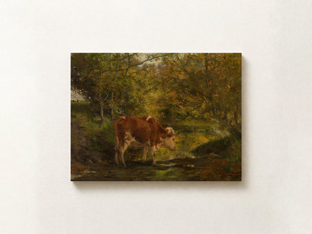 A rectangular canvas print of a classical landscape painting featuring a brown and white cow standing in a sunlit woodland stream, displayed on a textured off-white wall.
