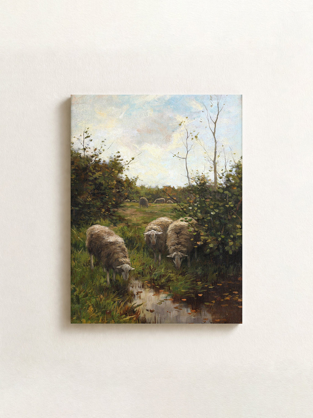 A horizontal canvas painting of a pastoral landscape featuring sheep grazing in a grassy field next to a river, displayed on a textured off-white wall.