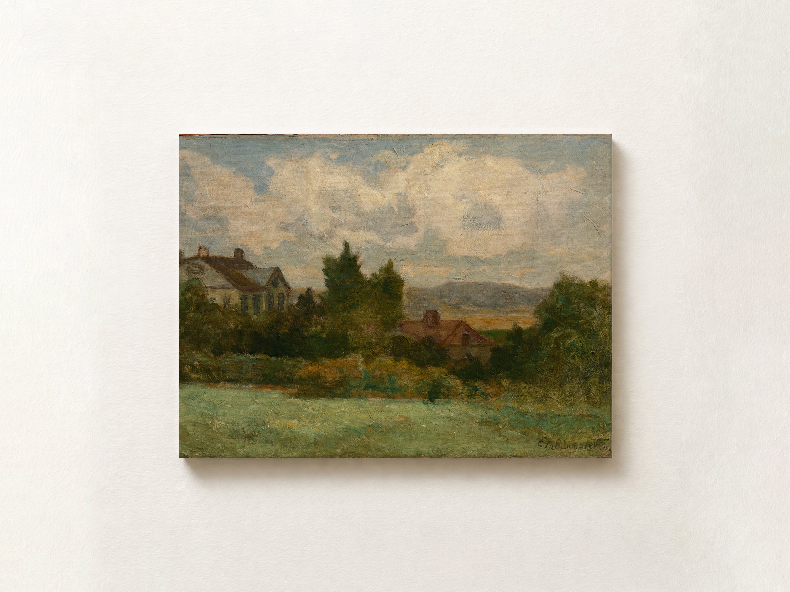 A framed landscape oil painting on canvas, depicting a rural scene with a house, trees, distant hills, and a cloudy sky, mounted on a textured off-white wall.