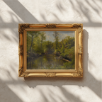 An ornate gold picture frame holding a landscape painting of a forest, mounted on a textured off-white wall with soft leaf shadows cast across it.