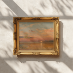 An ornate gold picture frame holding an abstract painting with warm orange, brown, and muted blue tones, mounted on a textured off-white wall with soft leaf shadows cast across it.