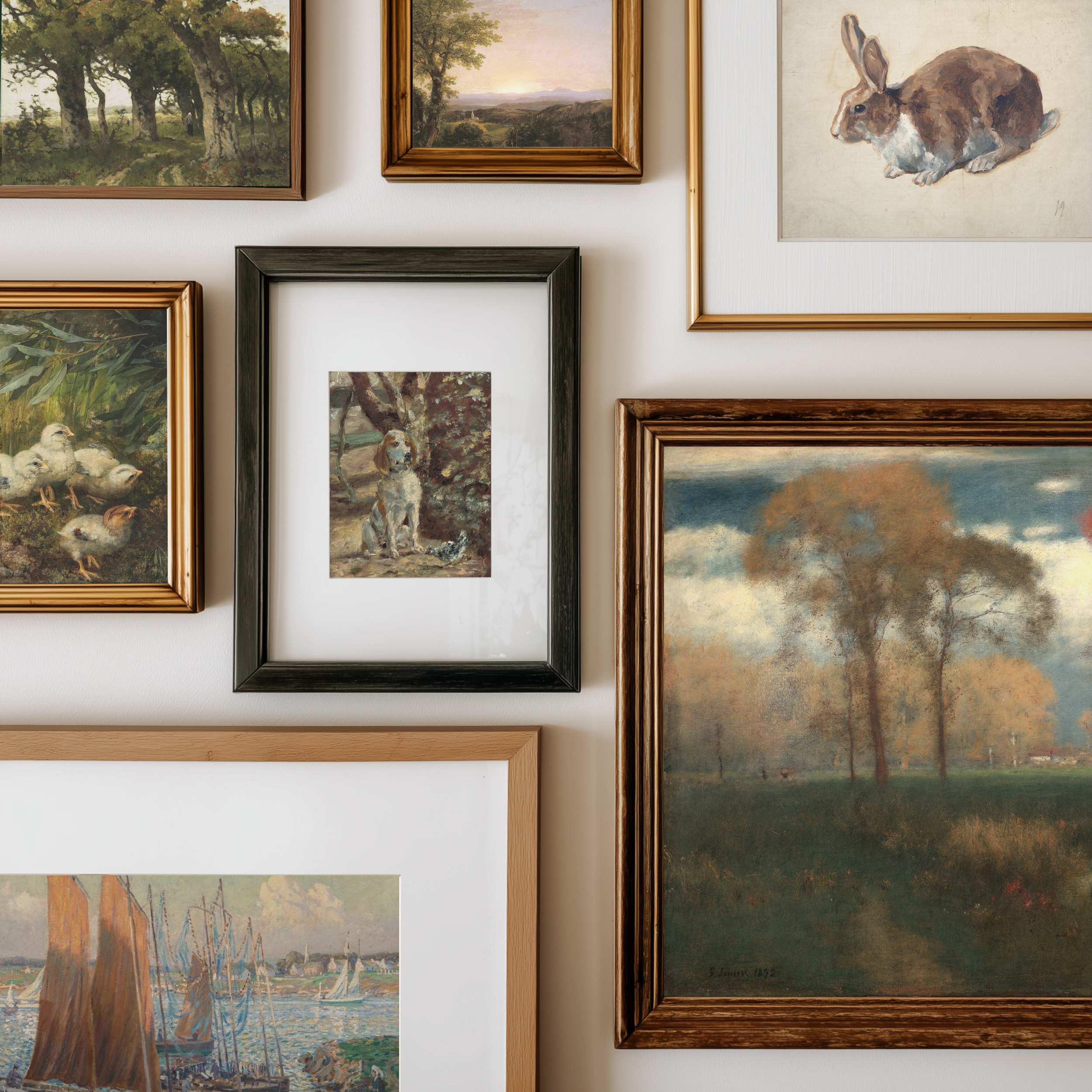 A gallery wall display of multiple framed art prints and paintings, including landscapes, a rabbit portrait, ducks, and a dog, each in different frame styles against a white wall.