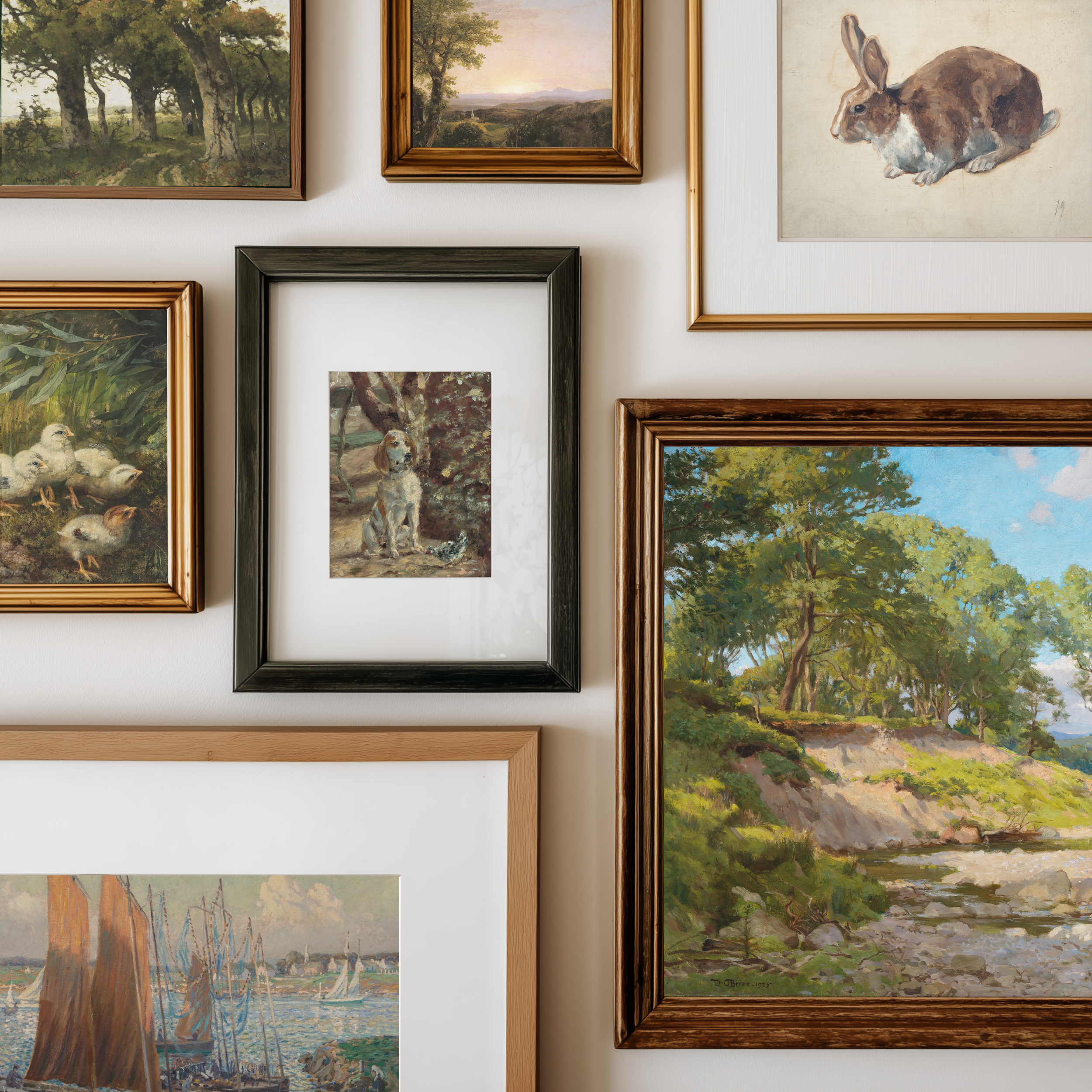 A gallery wall display of multiple framed art prints and paintings, including landscapes, a rabbit portrait, ducks, a dog, and a rabbit in a black frame, arranged on a white wall.