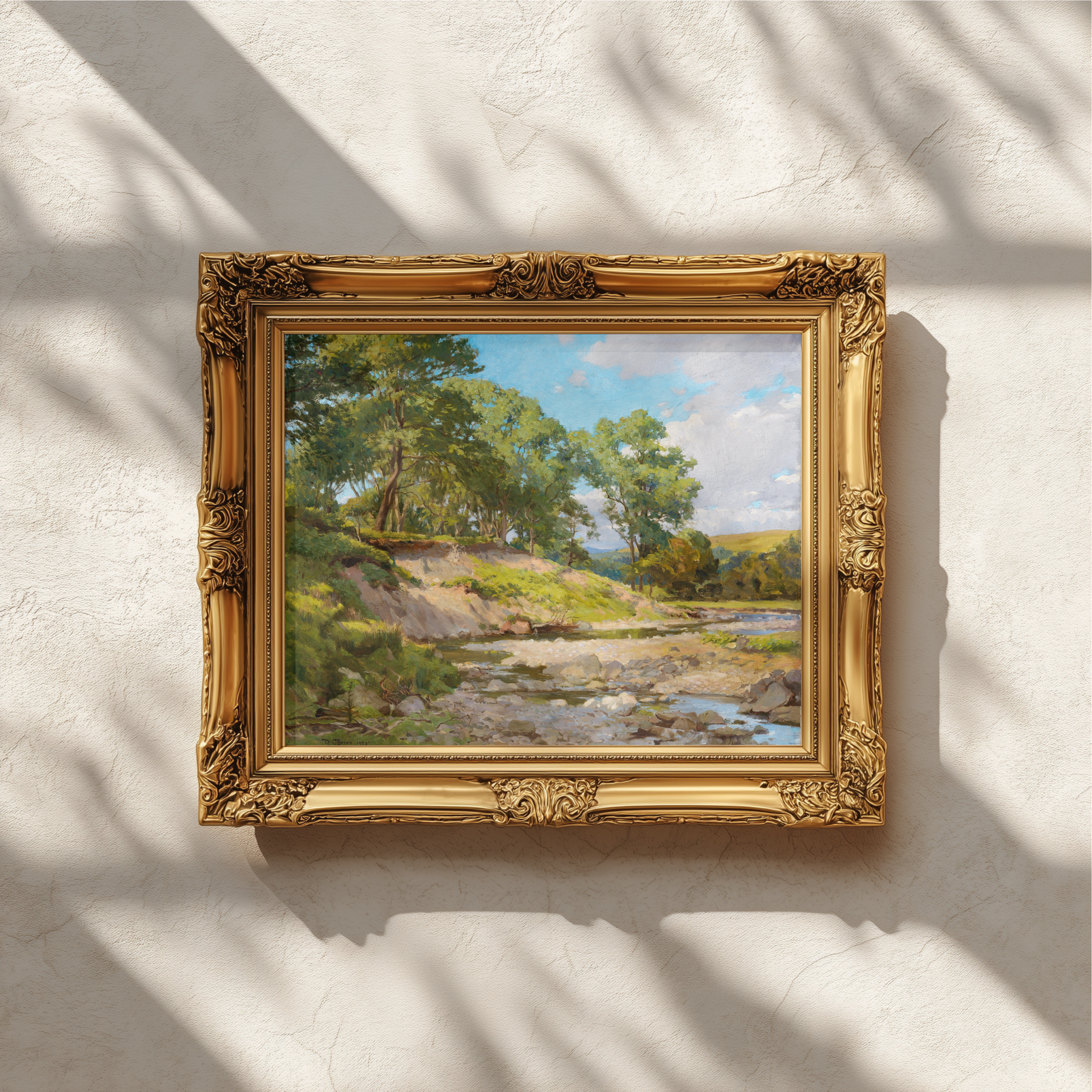An ornate gold picture frame holding a landscape painting with green trees, a river, and blue sky, mounted on a textured white wall with dappled sunlight and shadows.