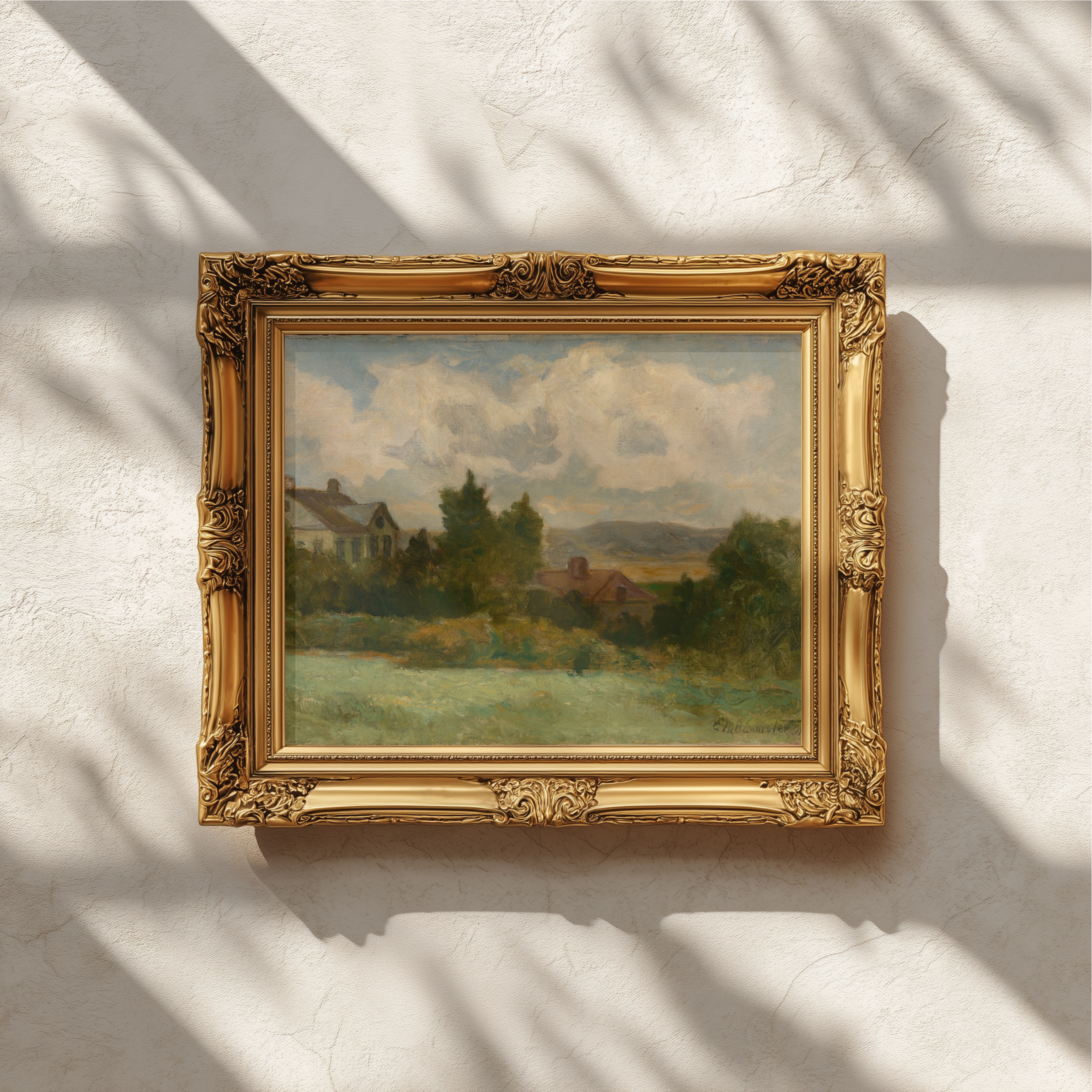 An ornate gold picture frame holding a landscape painting, mounted on a textured white wall with soft window shadow patterns.