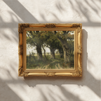 An ornate gold picture frame holding a landscape painting of a tree, mounted on a textured white wall with soft leaf shadows cast across it.