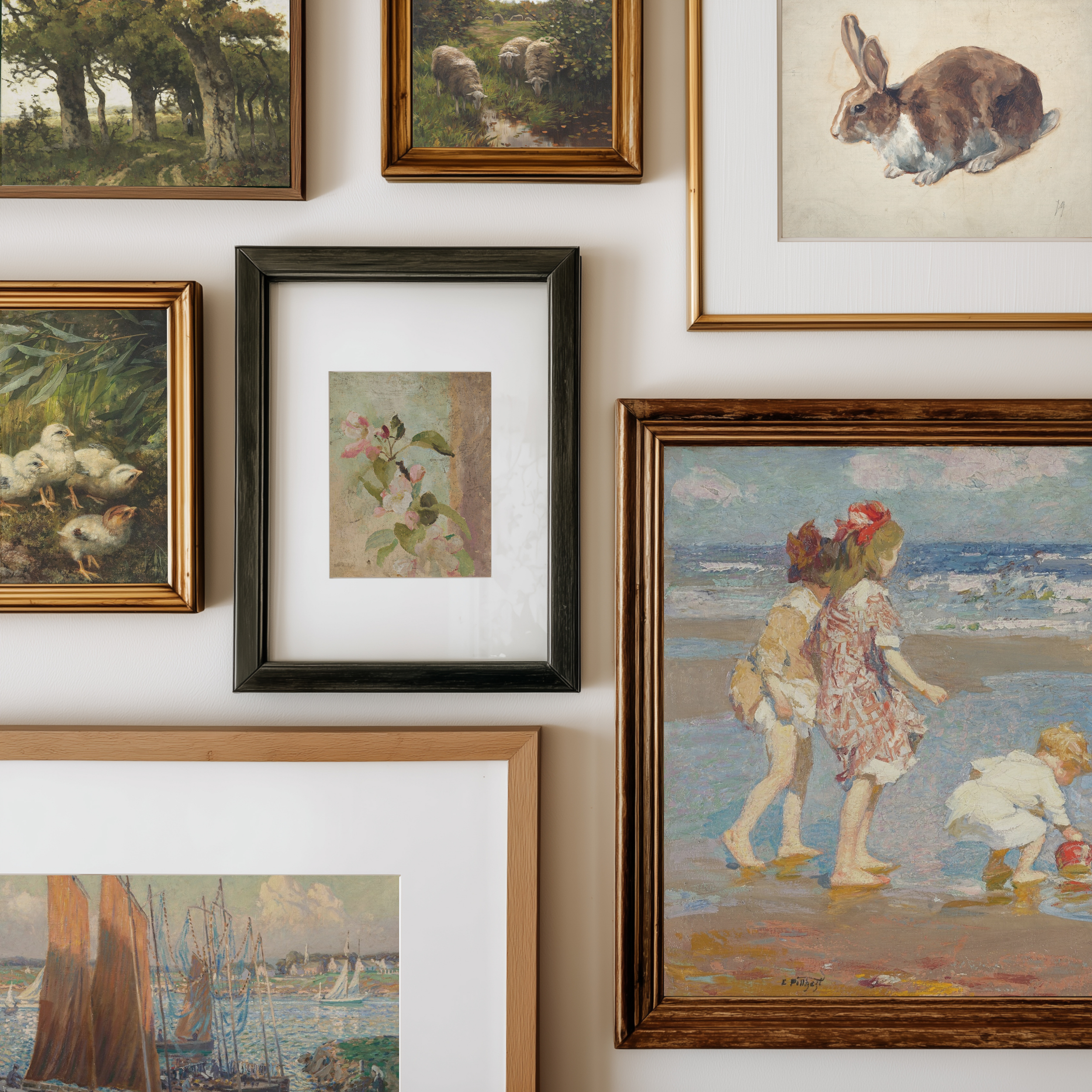 A gallery wall display of multiple framed art prints and paintings in various frames, including landscapes, portraits, and still life scenes, arranged on a light-colored wall.