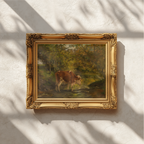An ornate gold-framed painting of a horse in a green landscape, mounted on a textured white wall with soft window shadow patterns.